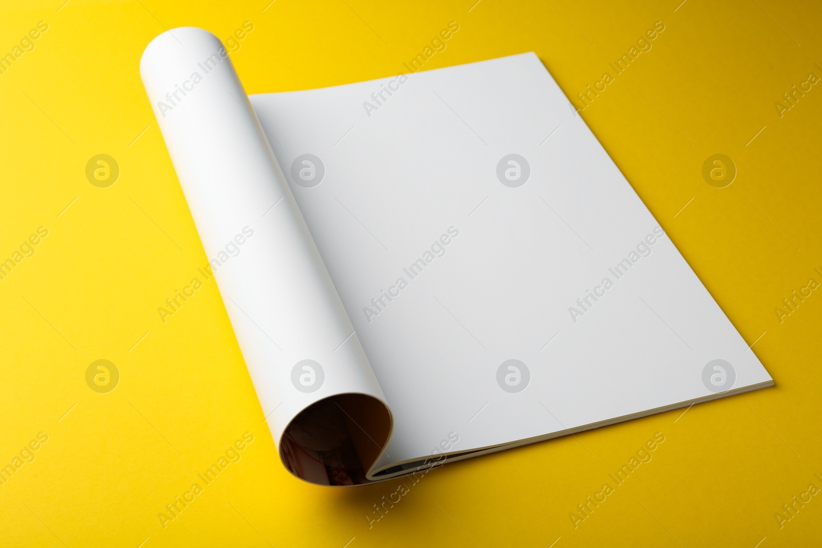 Photo of Open magazine with blank page on yellow background, closeup. Mockup for design