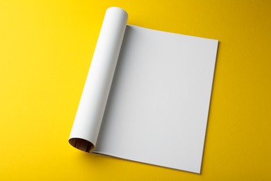 Open magazine with blank page on yellow background, above view. Mockup for design