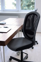 Black chair, laptop and desk in office