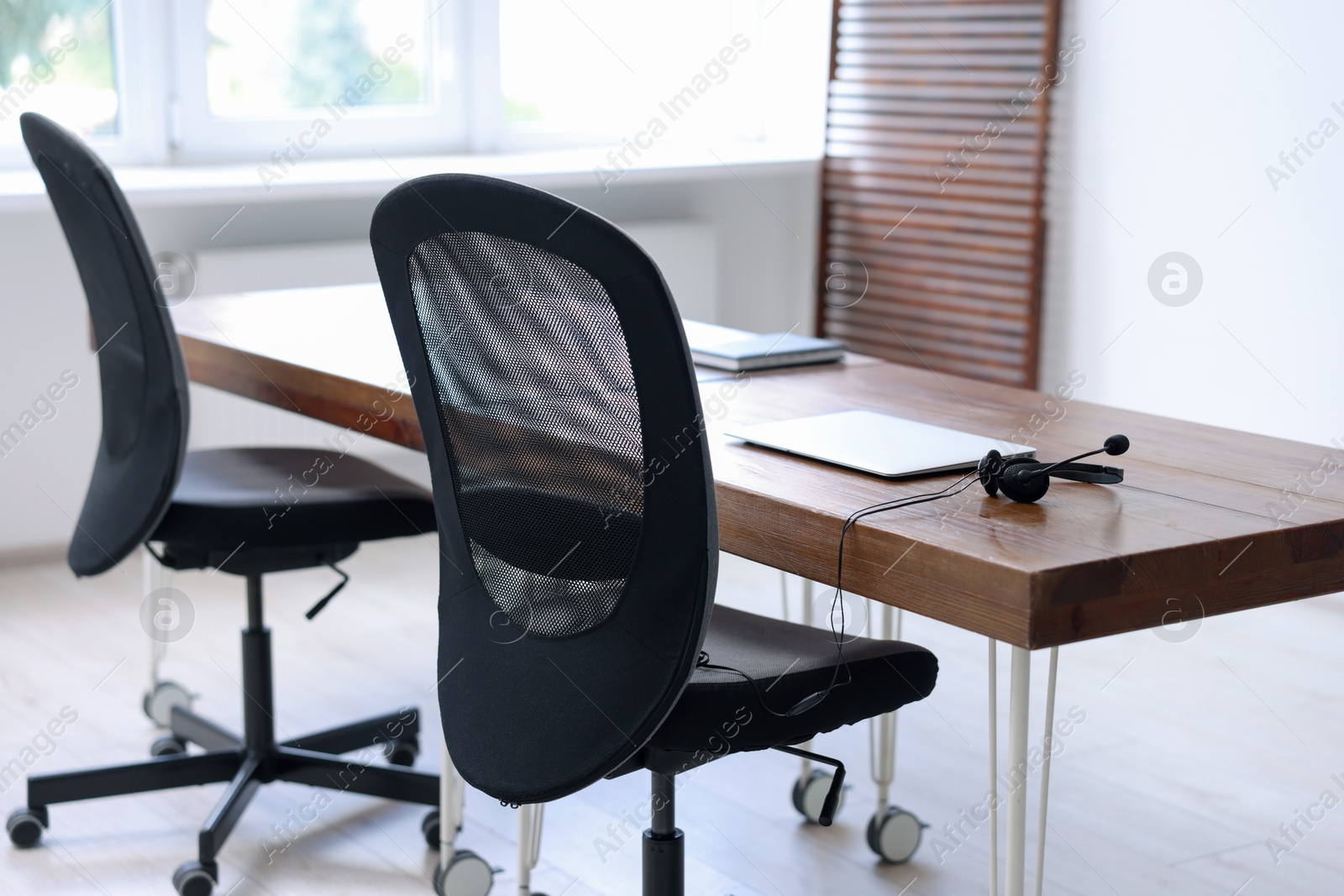 Photo of Black chairs, laptop and desk in office