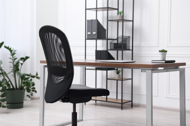 Black chair, laptop and desk in office