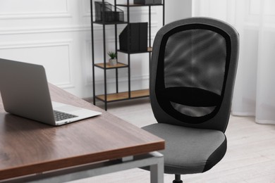 Photo of Black chair, laptop and desk in office