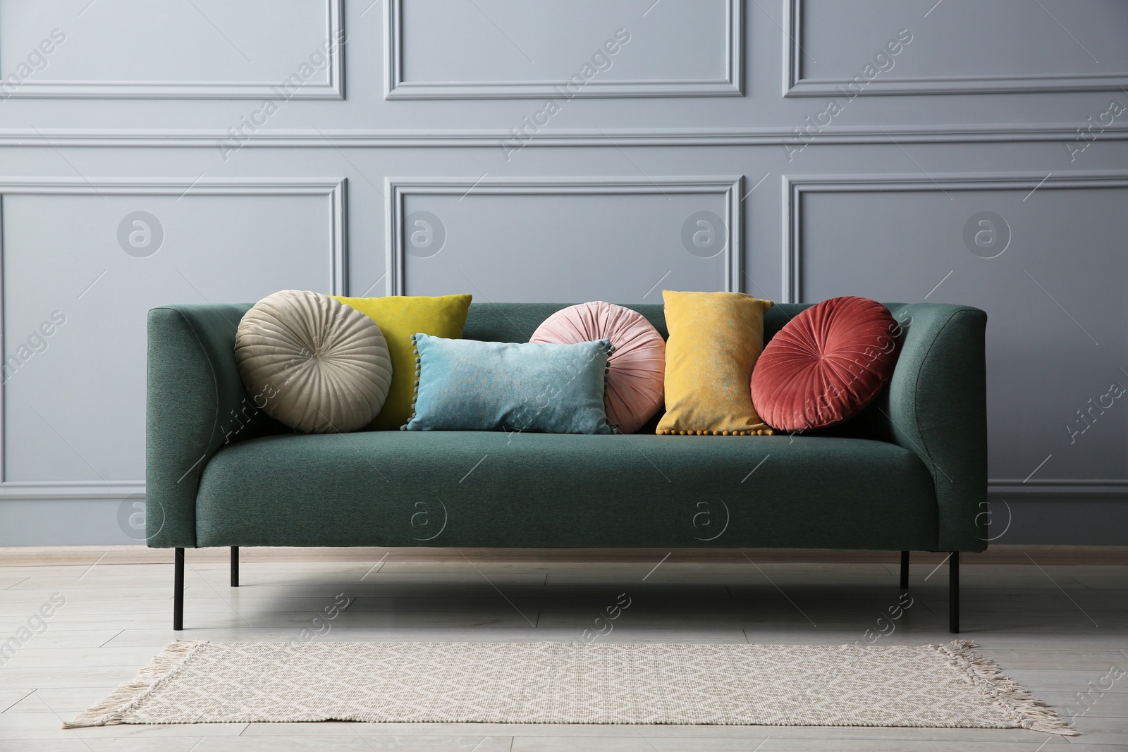 Photo of Stylish sofa with cushions near grey wall