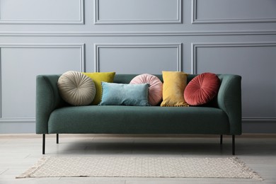 Stylish sofa with cushions near grey wall