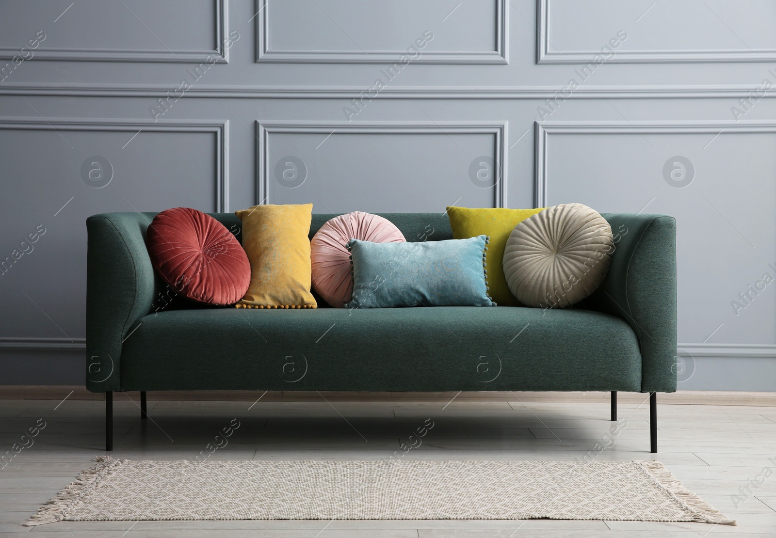 Photo of Stylish sofa with different cushions near grey wall