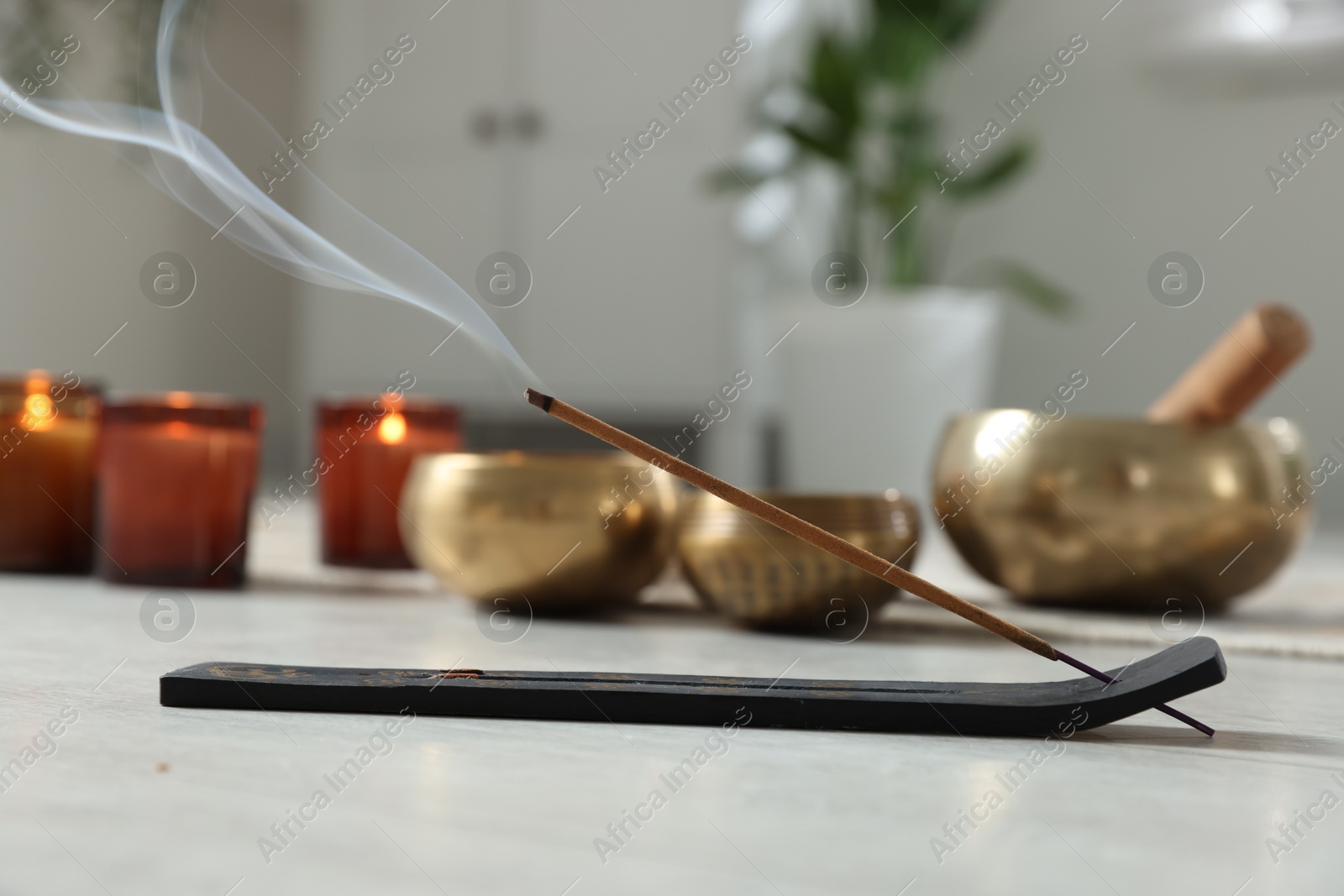 Photo of Incense stick smoldering in holder on floor indoors