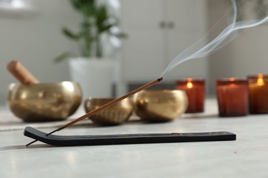 Photo of Incense stick smoldering in holder on white table