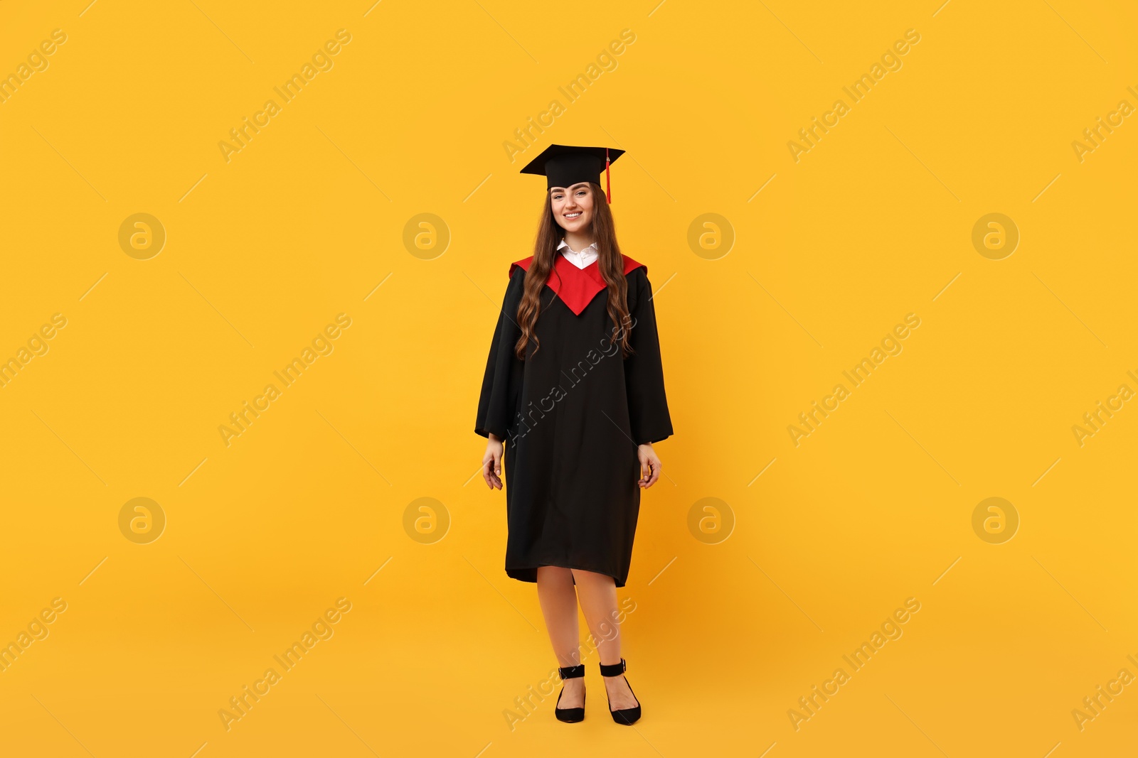 Photo of Happy student after graduation on orange background