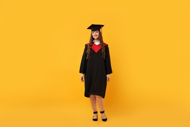 Happy student after graduation on orange background