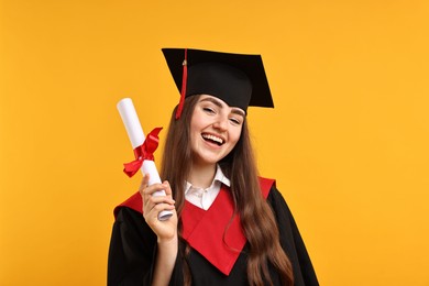 Photo of Happy student with diploma after graduation on orange background