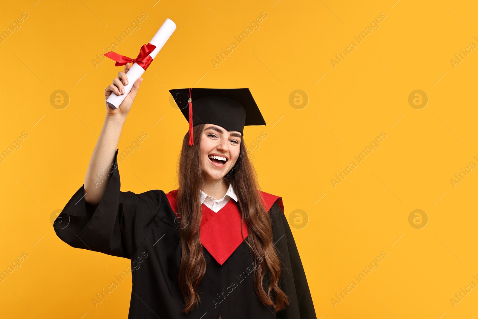 Photo of Happy student with diploma after graduation on orange background. Space for text