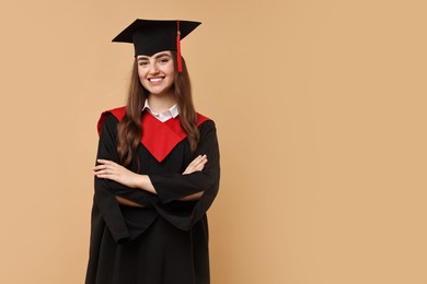 Happy student with crossed arms after graduation on beige background. Space for text