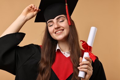 Happy student with diploma after graduation on beige background