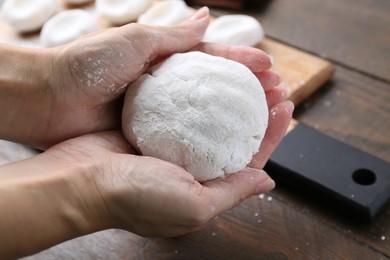 Photo of Woman making tasty mochi at wooden table, closeup