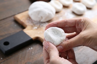 Photo of Woman making tasty mochi at wooden table, closeup