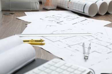 Photo of Different architectural drawings, dividers and ruler on wooden table