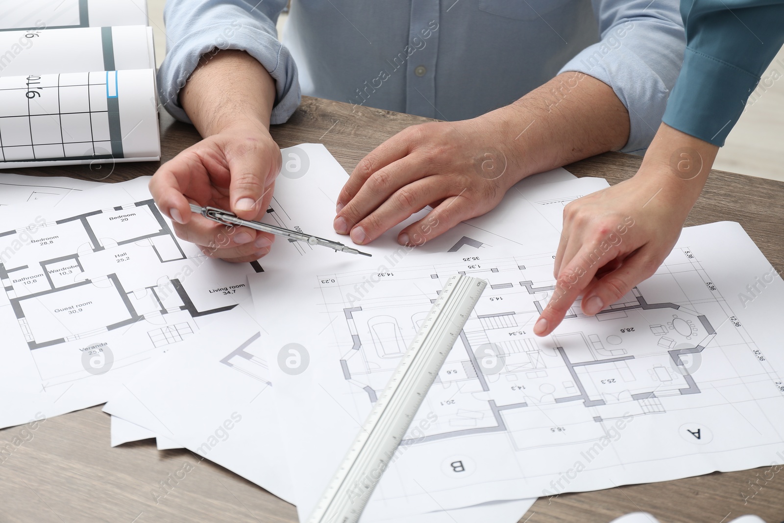 Photo of Architects working with project, closeup. Different technical drawings on wooden table