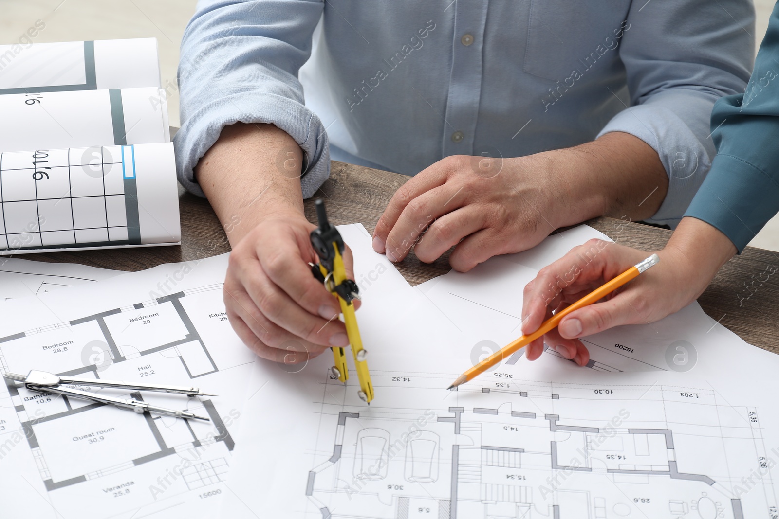 Photo of Architects working with project, closeup. Different technical drawings on wooden table