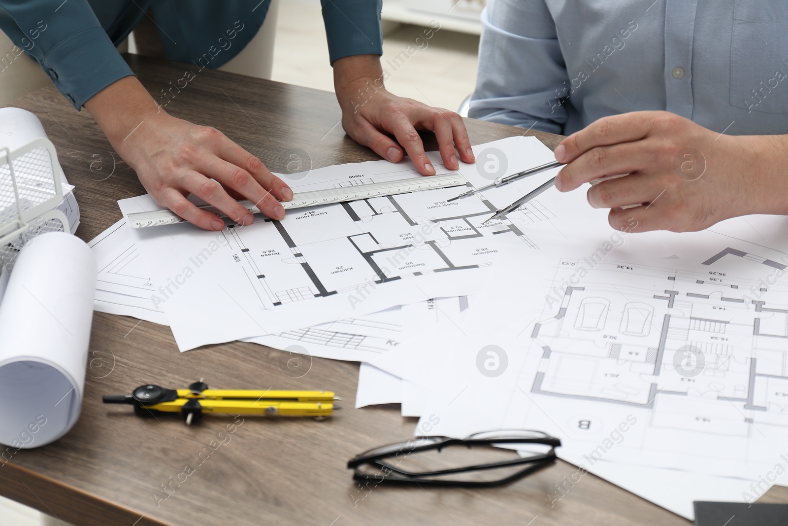 Photo of Architects working with project, closeup. Different technical drawings on wooden table