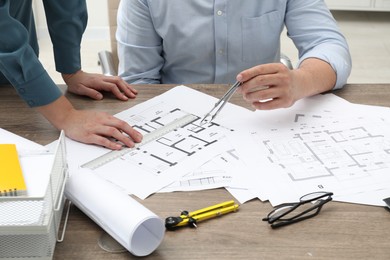 Photo of Architects working with project, closeup. Different technical drawings on wooden table