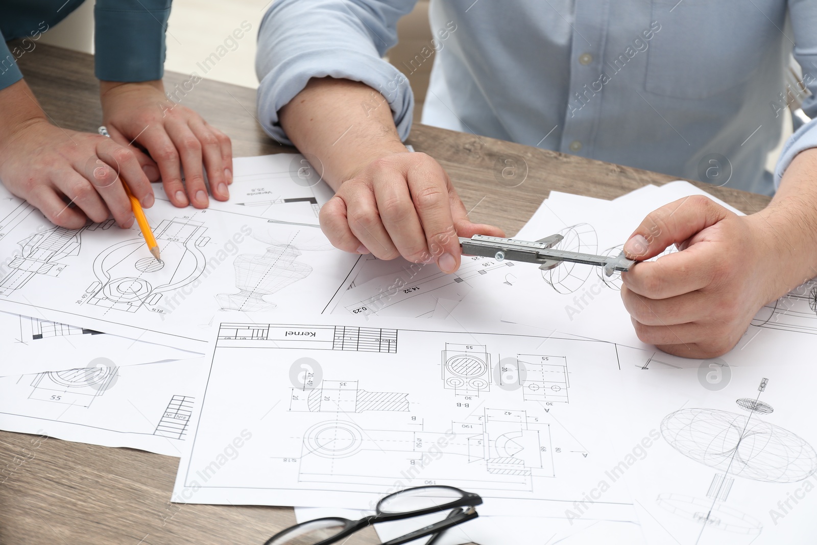 Photo of Engineers working with project, closeup. Different technical drawings on wooden table