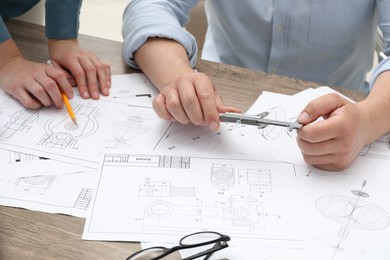 Photo of Engineers working with project, closeup. Different technical drawings on wooden table