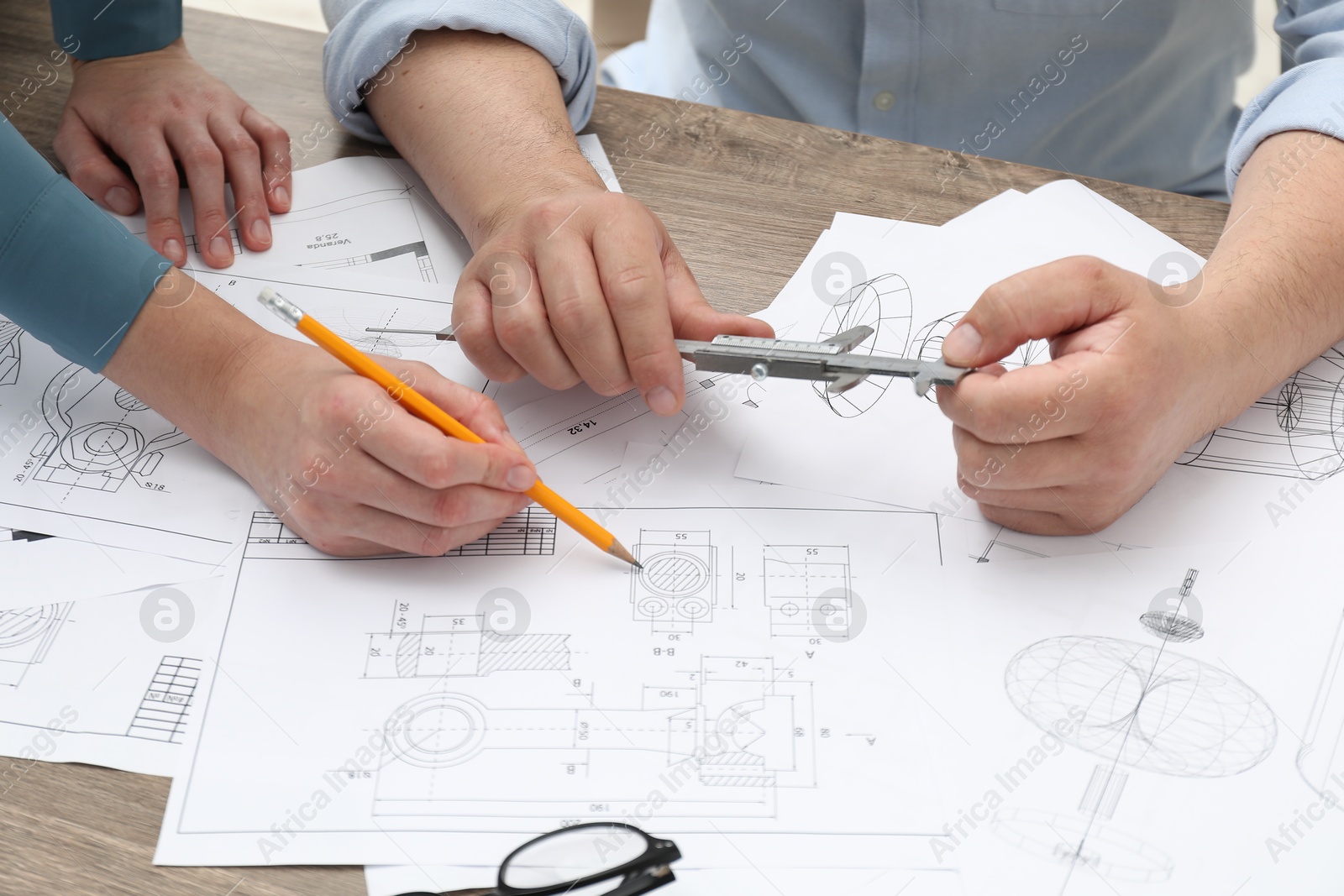 Photo of Engineers working with project, closeup. Different technical drawings on wooden table