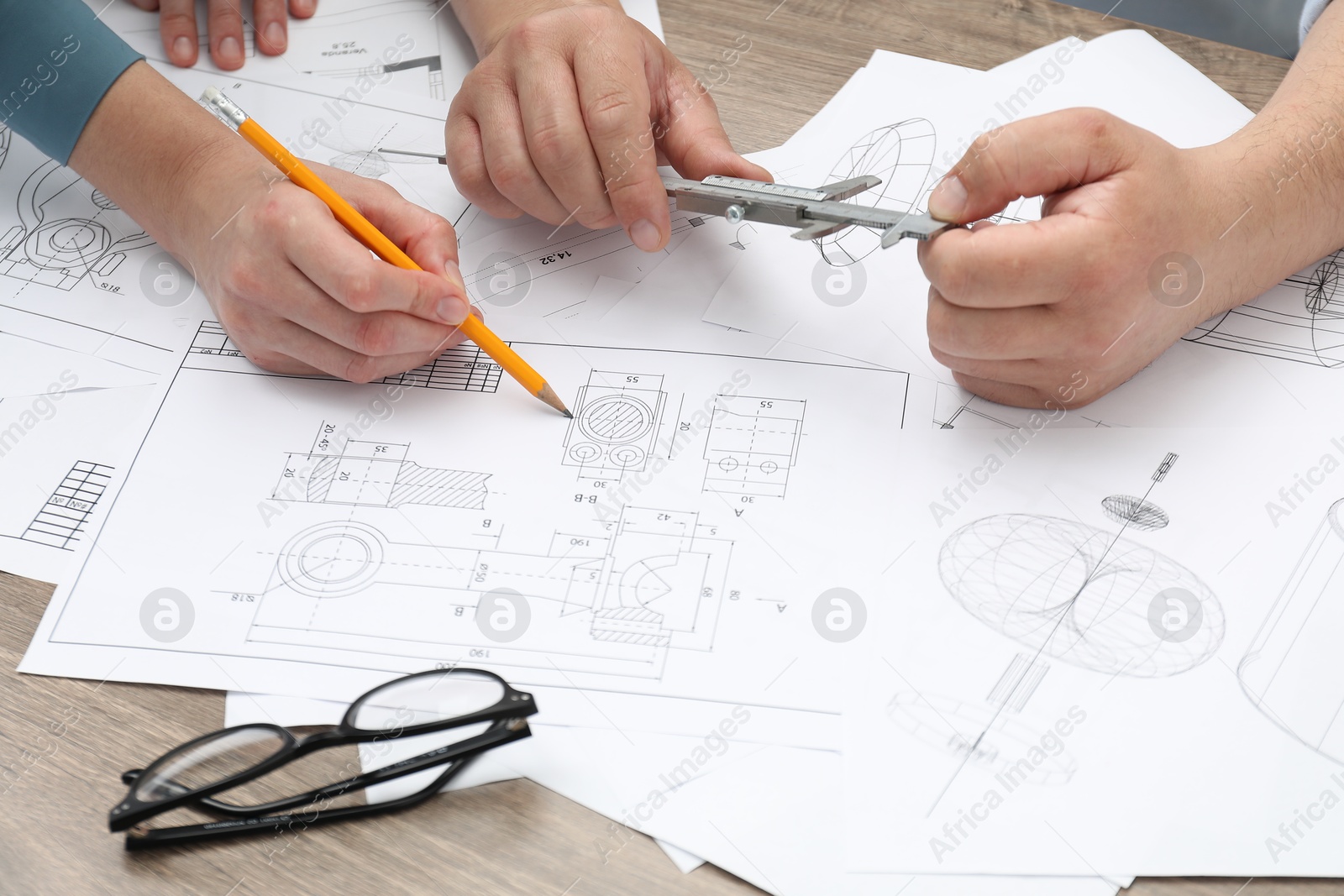 Photo of Engineers working with project, closeup. Different technical drawings on wooden table