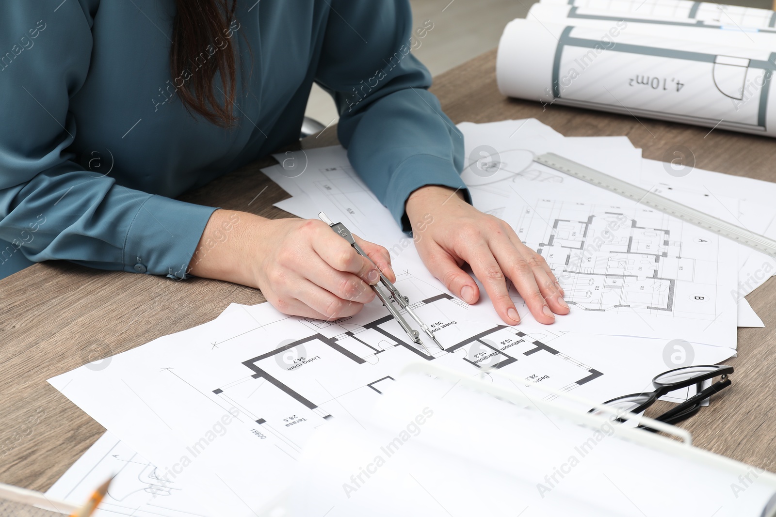 Photo of Architect working with project, closeup. Different technical drawings on wooden table