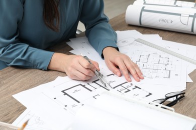 Photo of Architect working with project, closeup. Different technical drawings on wooden table