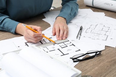 Photo of Architect working with project, closeup. Different technical drawings on wooden table