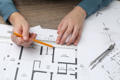 Photo of Architect working with project, closeup. Different technical drawings on wooden table