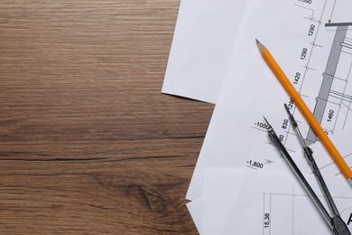 Photo of Different architectural drawings, pencil and divider on wooden table, flat lay. Space for text