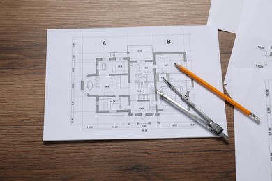 Different architectural drawings, pencil and divider on wooden table, flat lay