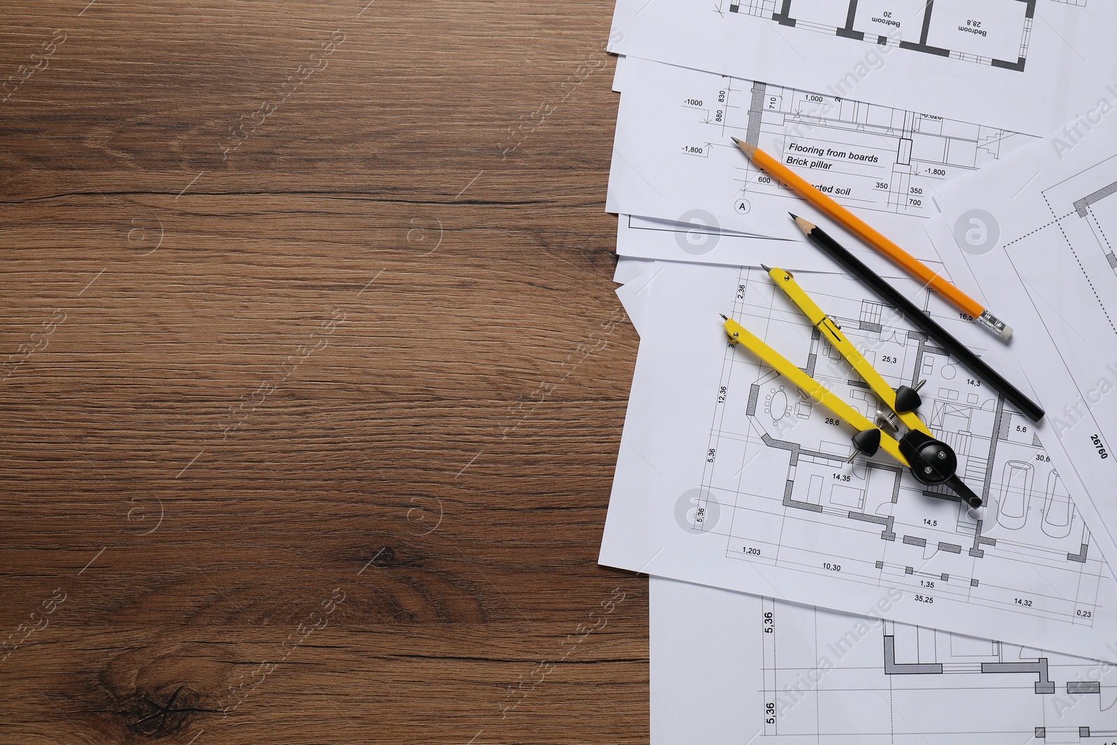 Photo of Different technical drawings, pencils and divider on wooden table, flat lay. Space for text