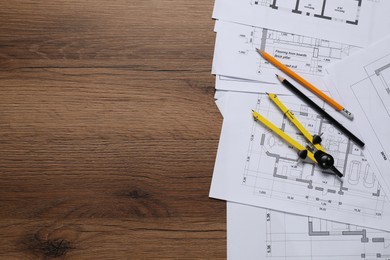 Photo of Different technical drawings, pencils and divider on wooden table, flat lay. Space for text