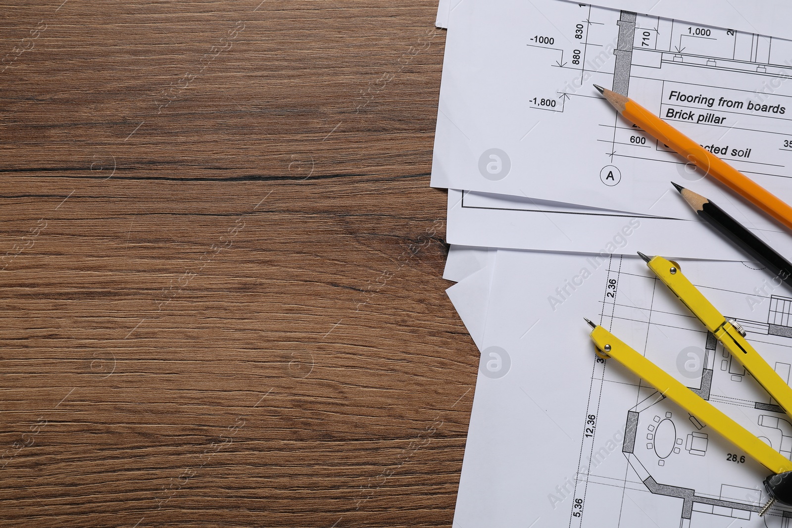 Photo of Different technical drawings, pencils and divider on wooden table, flat lay. Space for text