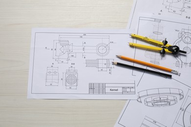 Different engineering drawings, pencils and divider on wooden table, flat lay