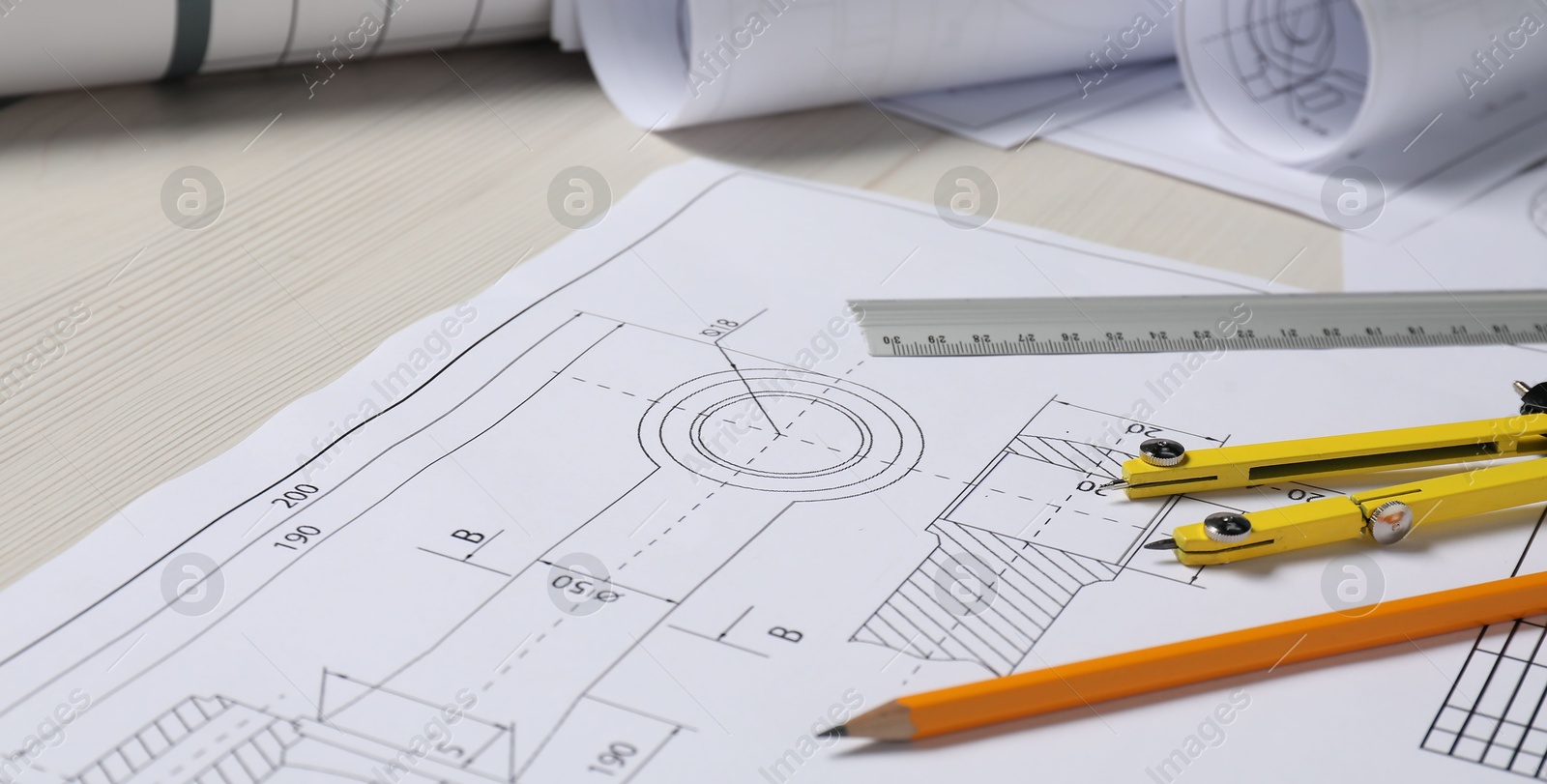 Photo of Different engineering drawings, pencil, ruler and divider on wooden table, closeup