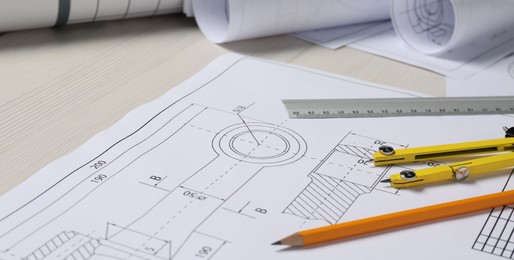 Photo of Different engineering drawings, pencil, ruler and divider on wooden table, closeup