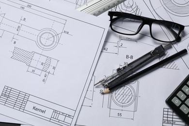 Different engineering drawings, pencil, divider and glasses on table, flat lay