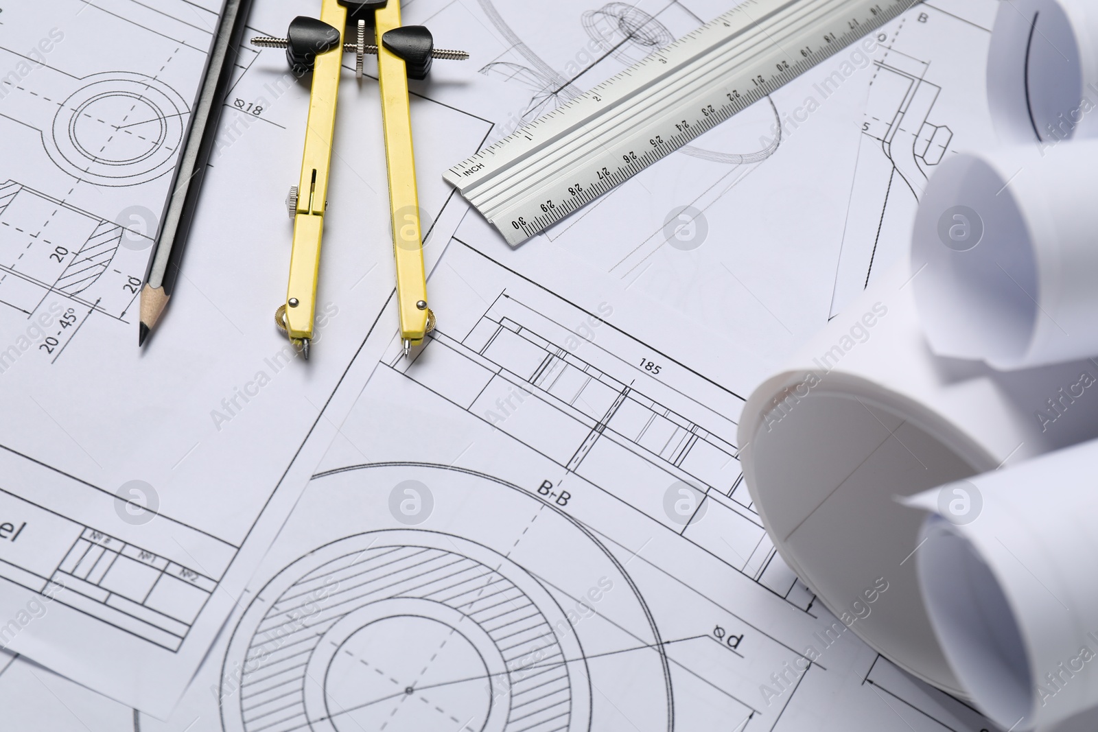 Photo of Different engineering drawings, ruler, divider and pencil on table