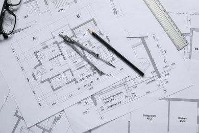 Different architectural drawings, ruler, divider, pencil and glasses on table, flat lay