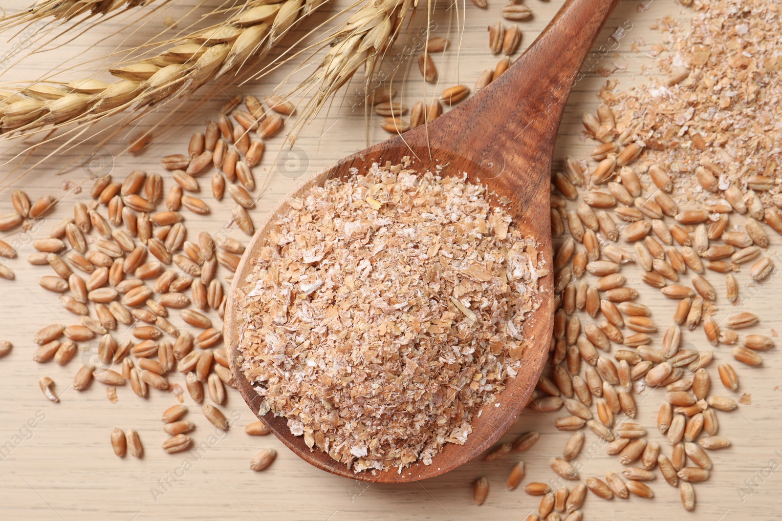 Photo of Wheat bran, kernels and spikelets on wooden table, flat lay