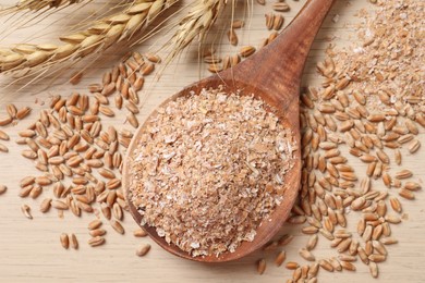 Photo of Wheat bran, kernels and spikelets on wooden table, flat lay