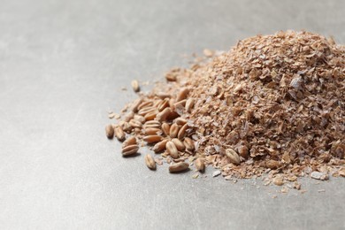 Photo of Pile of wheat bran on grey table, space for text