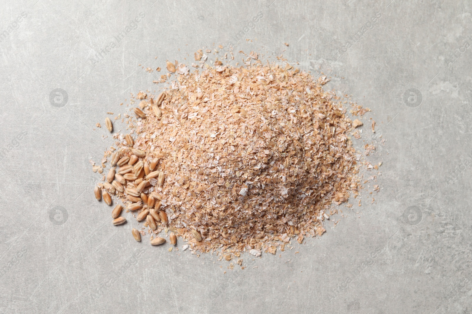 Photo of Pile of wheat bran on grey table, top view