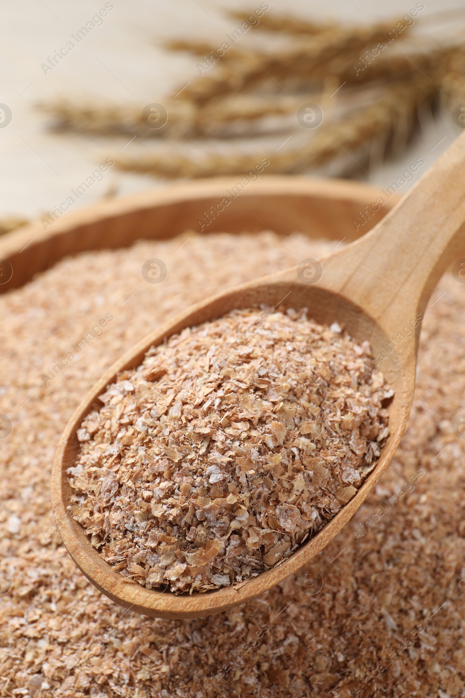 Photo of Spoon of wheat bran above bowl, closeup