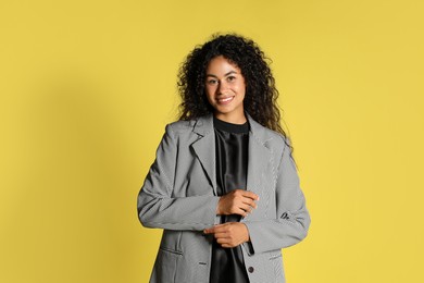 Beautiful woman in stylish jacket on yellow background