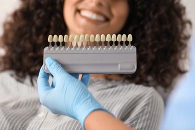 Photo of Doctor checking young woman's teeth color in clinic, closeup. Dental veneers